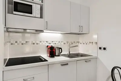 a white kitchen with a sink and a microwave at Les Oranges Five Stars HolidayHouse in Nice