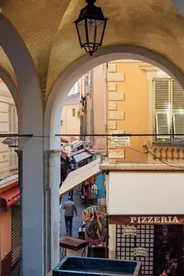 an alley with arches in a city with a man walking down the street at 