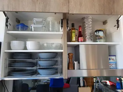 a kitchen cabinet with plates and dishes in it at Maison / Appart Le PIOL in Nice