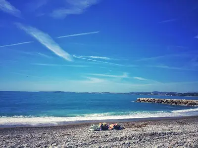 two people laying on a beach near the ocean at Villa du Cros in Cagnes-sur-Mer