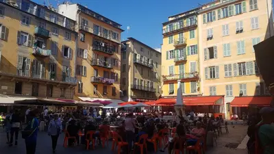 a group of people sitting at tables in front of buildings at Nissa La Bella in Nice