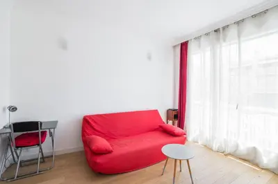 a red couch in a room with a window at Studio Guiglia - Welkeys in Nice