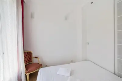 a bedroom with a white bed and a chair at Studio Guiglia - Welkeys in Nice