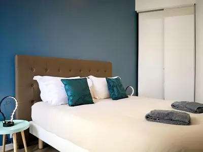 a bedroom with a large white bed with blue walls at Appartement Urban 3 in Nice