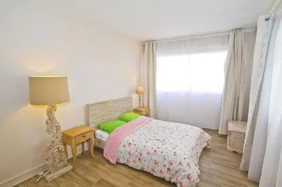 a bedroom with a bed with green pillows and a window at MILORD PROMENADE 2 - PROMENADE HOLIDAY in Nice