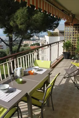 a table and chairs sitting on a balcony at Oasis Méditerranéen Piscine & Parking Calme absolu in Nice