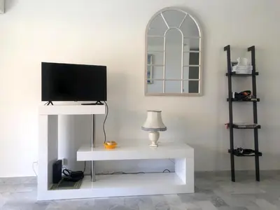 a living room with a tv on a white table at Oasis Méditerranéen Piscine & Parking Calme absolu in Nice