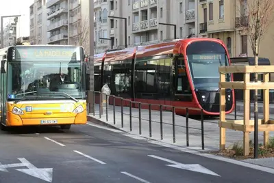a yellow and red bus driving down a city street at Le Californie Côte d'azur plage les pieds dans L'eau in Nice