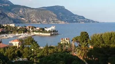 a view of a town on the water with mountains at Les Jasmins in Beaulieu-sur-Mer
