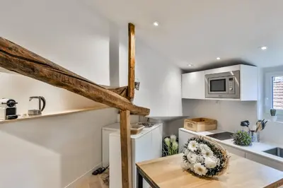 a kitchen with white cabinets and a wooden table at MY CASA - LA CIVETTE - Place Garibaldi in Nice