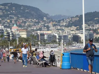 a group of people walking on a pier near a beach at Palais des Domes Gloria in Nice