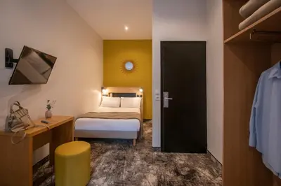 a small bedroom with a bed and a door at Hotel d'Ostende in Nice