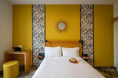 a hotel room with a bed and a yellow wall at Hotel d'Ostende in Nice
