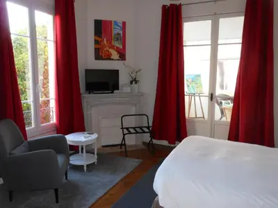 a bedroom with red curtains and a bed and a fireplace at Hotel Villa Les Cygnes in Nice