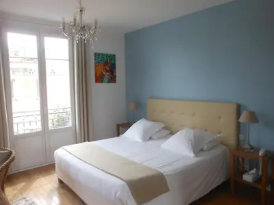 a bedroom with a large white bed with a chandelier at Hotel Villa Les Cygnes in Nice