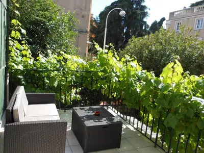 a patio with chairs and a fence with plants at Hotel Villa Les Cygnes in Nice