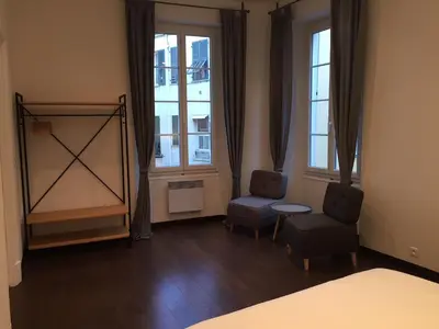 a bedroom with a bed and two chairs and windows at Port de Nice in Nice