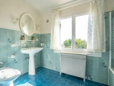 a blue tiled bathroom with a sink and a window at Holiday Home La Mesnière by Interhome in Gattières