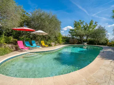a swimming pool with two chairs and an umbrella at Holiday Home La Mesnière by Interhome in Gattières