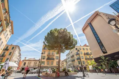 a street in a city with a tree and buildings at Place Du Pin in Nice
