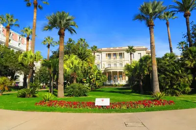 a building with palm trees and a sign in a park at Nestor&Jeeves - HOUSE OF CARDS - Central - Very close sea in Nice