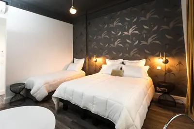 two beds in a hotel room with a wall mural at Arome Hôtel in Nice