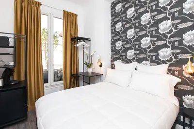 a bedroom with a white bed with a floral wallpaper at Arome Hôtel in Nice
