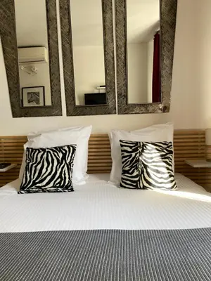a bed with two zebra pillows and three mirrors at Intérieurs-Cour in Nice