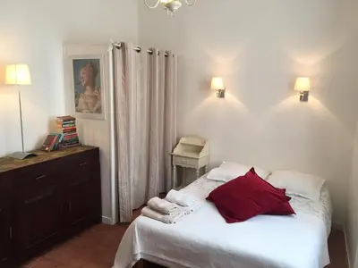 a bedroom with a bed with white sheets and red pillows at Studios Floreal in Nice