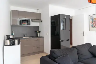 a living room with a couch and a kitchen at Place du Pin in Nice