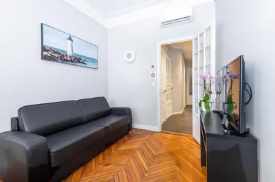 a living room with a black couch and a television at Nice Central Art Deco Flat 45 m² in Nice