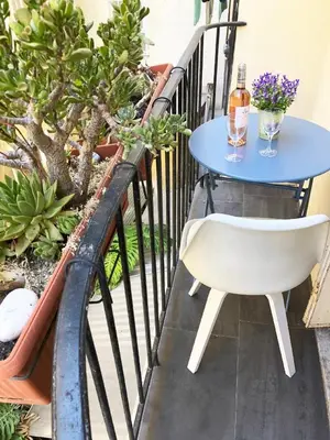 a table and chair on a balcony with a bottle of wine at Nice Central Art Deco Flat 45 m² in Nice