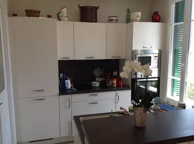 a kitchen with white cabinets and a table at Appartement Tout Confort avec Terrasse in Nice