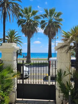 a gate at the beach with palm trees and the ocean at Hotel Flots d'Azur Promenade des Anglais in Nice