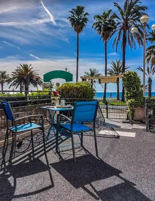 a table and chairs with the beach in the background at Hotel Flots d'Azur Promenade des Anglais in Nice