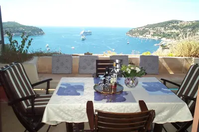 a table with chairs and a view of the ocean at RESIDENCE DU CAP AP2027 - Villefranche-sur-Mer, by Riviera Holiday Homes in Villefranche-sur-Mer