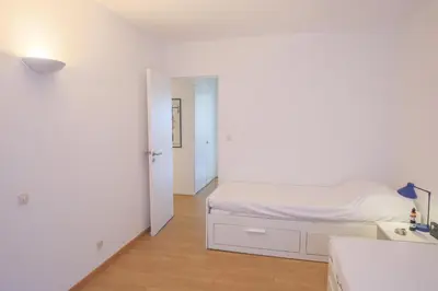 a white bedroom with a bed and a hallway at Jardin Figuiers AP4123 by Riviera Holiday Homes in Villefranche-sur-Mer