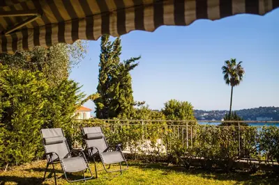four chairs sitting in the grass under an umbrella at Jardin Figuiers AP4123 by Riviera Holiday Homes in Villefranche-sur-Mer