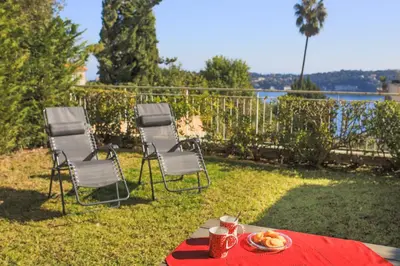 a table and chairs with a plate of food on it at Jardin Figuiers AP4123 by Riviera Holiday Homes in Villefranche-sur-Mer