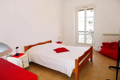 a bedroom with a large white bed and a red couch at LIBERATION - Nice in Nice