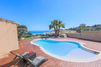 a swimming pool on a patio with chairs and the ocean at CORNICHE D'ARGENT - Nice in Nice