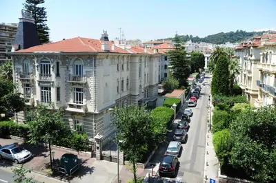 a white building with black windows and a palm tree at Suite ST Geneviève Five stars holiday house in Nice
