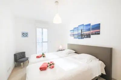 a white bedroom with two beds with flowers on them at JARDINS MASSENA AP4088 Nice, by Riviera Holiday Homes in Nice