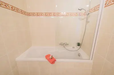 a bath tub with a shower and a red towel at JARDINS MASSENA AP4088 Nice, by Riviera Holiday Homes in Nice