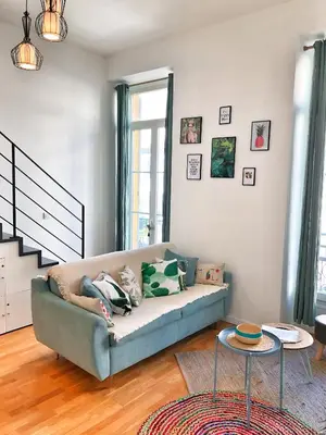 a person laying on a couch in a living room at Homelivia, Appart FRIDA, mezzanine, déco raffinée et balcon in Nice