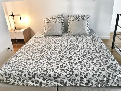 a bed with a black and white comforter and pillows at Homelivia, Appart FRIDA, mezzanine, déco raffinée et balcon in Nice