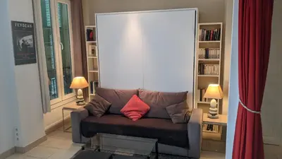 a living room with a couch with a red pillow at Charmant studio tout proche du port in Nice