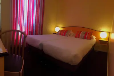 a bedroom with a bed with two pillows and red curtains at Hotel Arc En Ciel in Èze