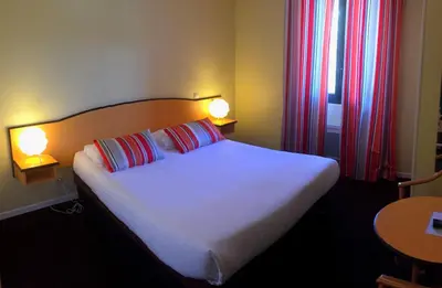 a bedroom with a bed with two pillows and two lamps at Hotel Arc En Ciel in Èze