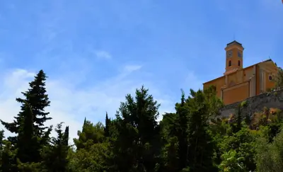 a building on top of a hill with a clock tower at Hotel Arc En Ciel in Èze